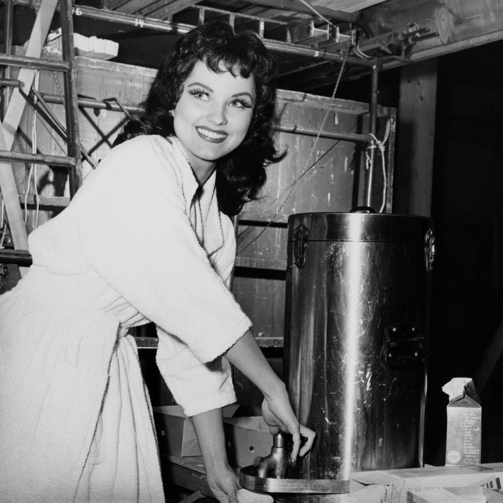 #32 Debra Paget helps herself to coffee on the set of the Panoramic Productions film ‘The Gambler from Natchez’, 1954