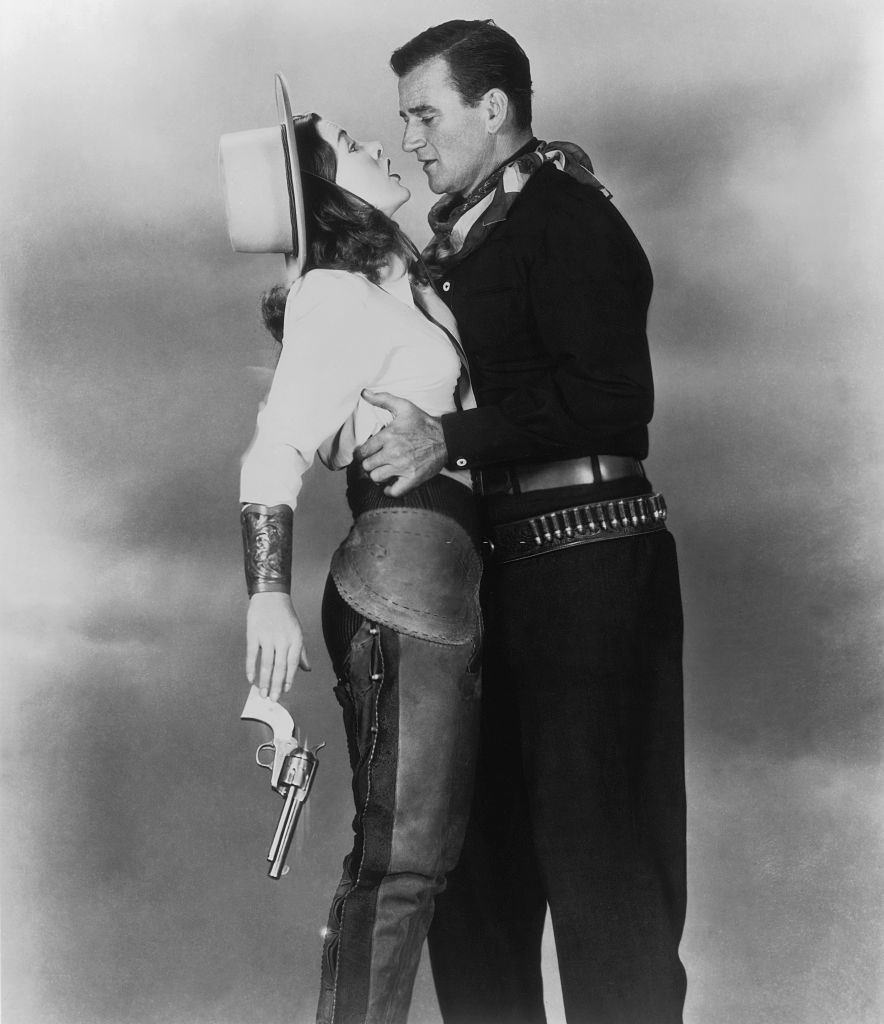 Ella Raines with John Wayne on the movie set of “Tall in the Saddle” (L’Amazone aux Yeux Verts), directed by Edwin L. Marin.