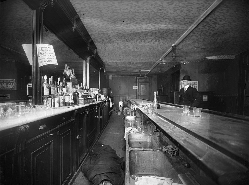 A piece of paper over the body of a man in a bar says ‘trust no more’, early 1900s New York