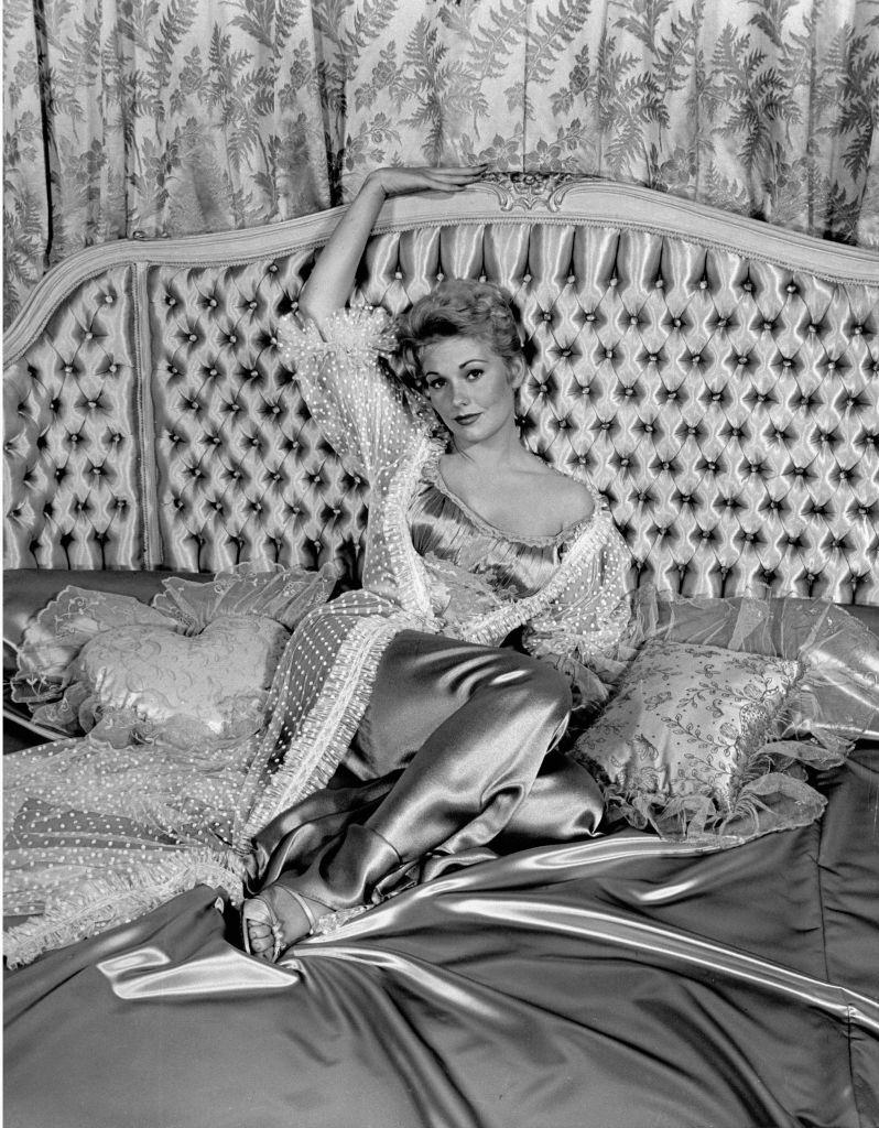 #41 Kim Novak, lounging on satin bed.