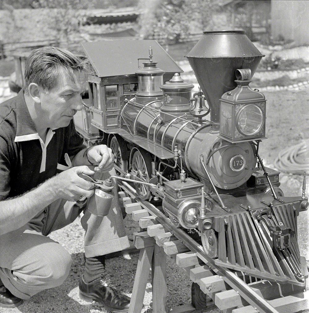 #20 Walt Disney oiling parts of the locomotive of his scale model steam railroad, the Carolwood Pacific Railway, in the backyard of his house in Los Angeles, September 1951