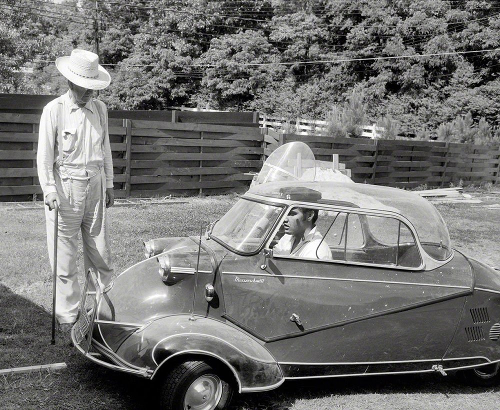 #26 Elvis Presley in 1956 at home in Memphis with his three-wheeled Messerschmitt “bubble car” and Harley-Davidson motorcycle, and grandfather Jessie Presley.