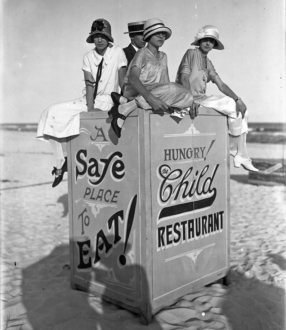 #57 Young ladies at Pensacola Beach sitting atop a sign for the Child Restaurant, circa 1935