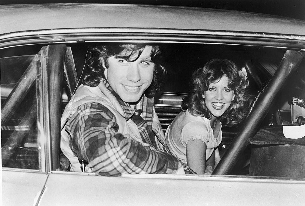 John Travolta with Nancy Allen pose in a car on the set of the film, ‘Carrie,’ directed by Brian De Palma, 1976