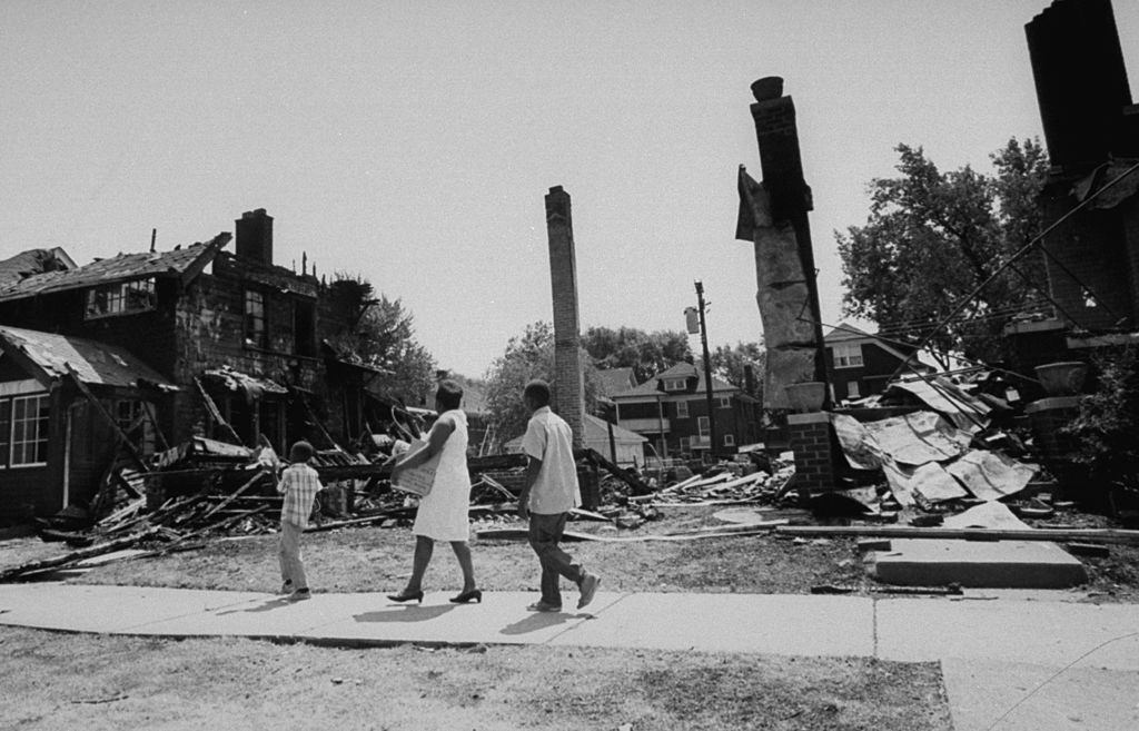 #48 Aftermath of Detroit race riots, family walking past rubble from gutted buildings, Detroit, 1967