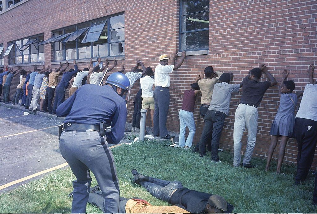 #50 Policeman lining up suspects after race riots, 1967