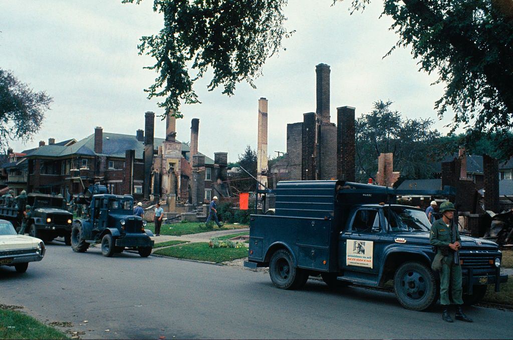 #24 Soldiers patrol along row of fire-gutted homes following the riot, Detroit, 1967