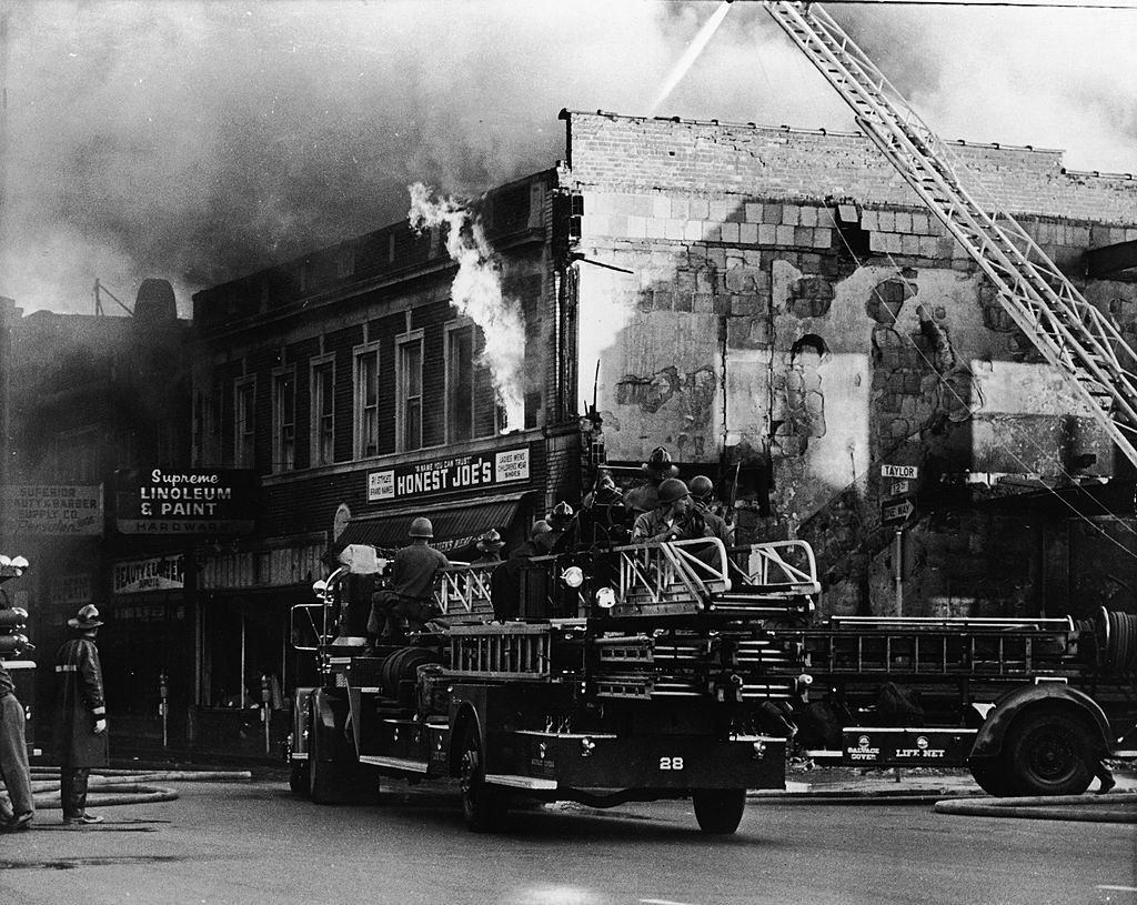 #31 Federal troops ride on a fire engine to protect the firefighters from snipers during the riots in Detroit, 1967