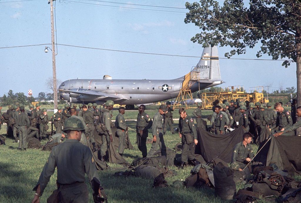 #38 US National Guard troops as they sort equipment in a field near a Lockheed C-130 Hercules transport plane, Detroit, 1967