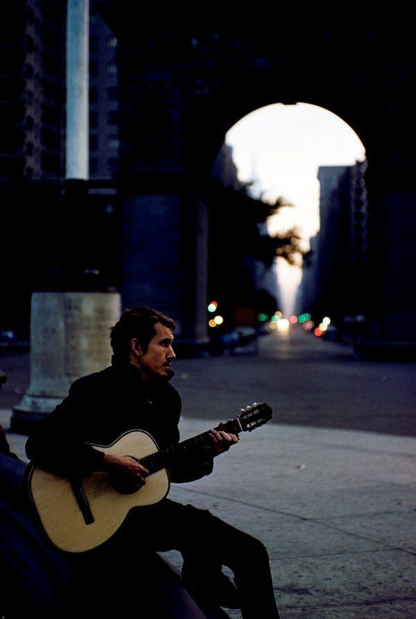 #16 A man plays guitar at dusk in Washington Square Park in 1959.
