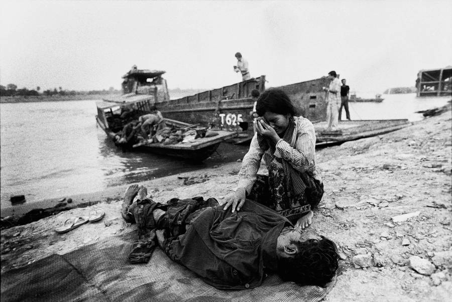 #51 A distraught woman cries over the body of her husband, killed by Khmer Rouge soldiers, Phnom Penh. 1975.