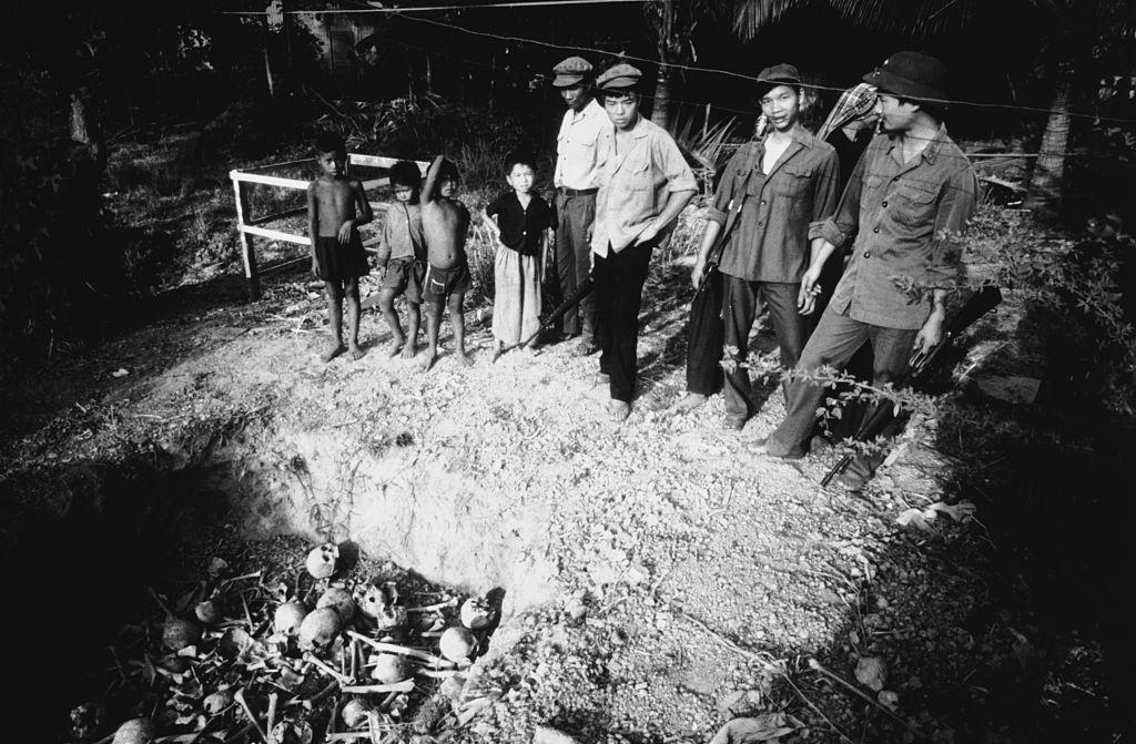 #9 Vietnamese soldiers and a group of children witness the unearthing of a mass grave, 1980