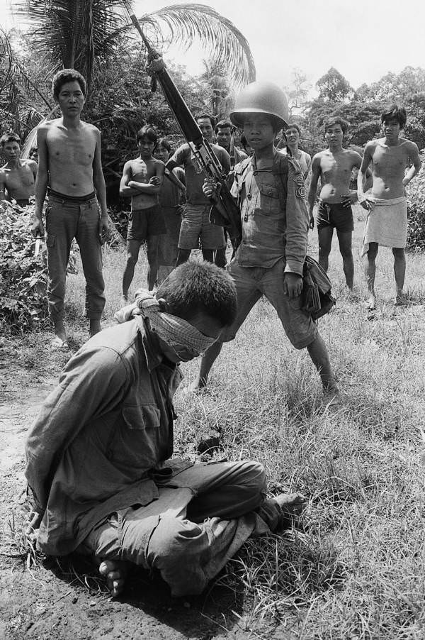 A child soldier stands over a blindfolded soldier, Angkor Chey, Cambodia. 1973.