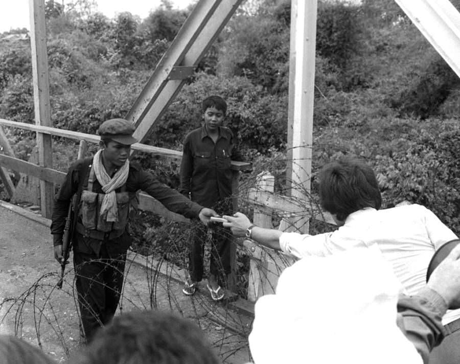 #21 An employee at the French Embassy offers a cigarette to a Khmer Rouge soldier, Phnom Penh, 1975.