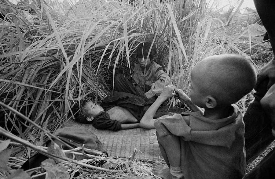 #24 Young refugees hide under tall grass, escaping from the killing fields of the Khmer Rouge, Aranyaprathet, Thailand, 1979.