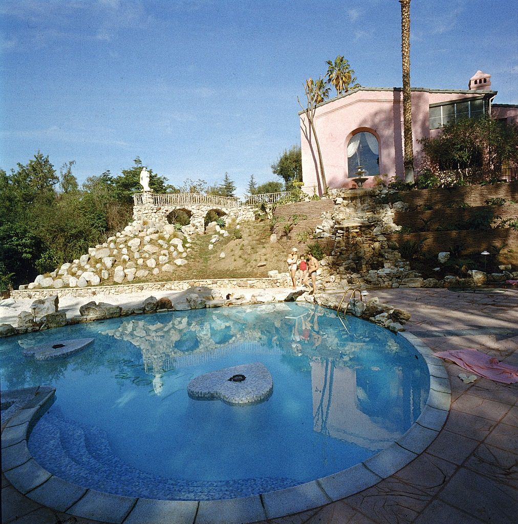 #11 Jayne Mansfield and her familiy stand on the far side of the heart-shaped pool in their backyard, Pink Palace
