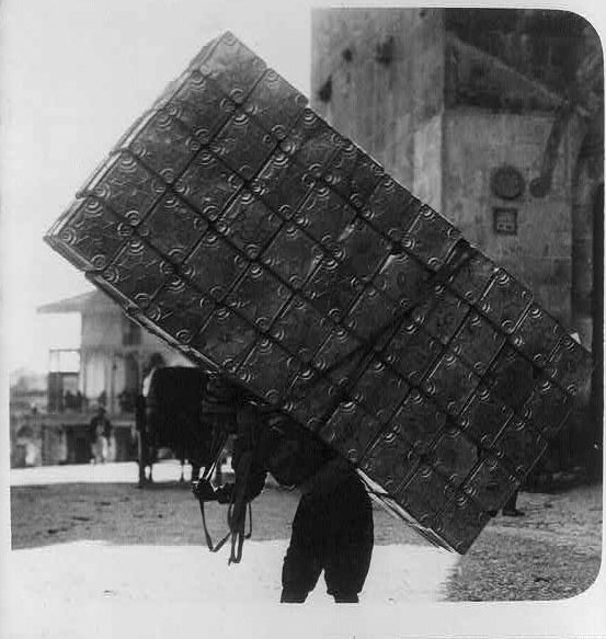 #22 A porter carrying 50 empty petrol tins on his back, Circa 1914-1918