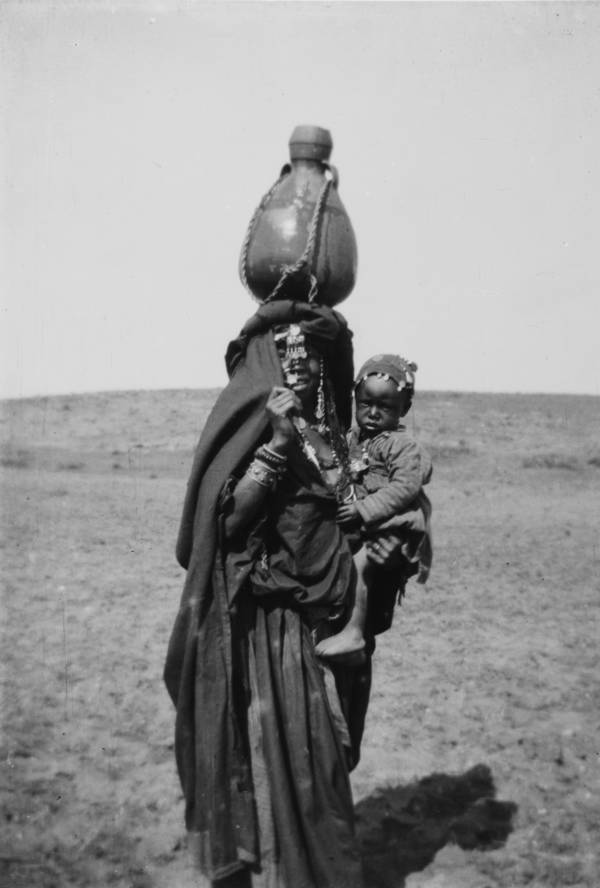 #33 A mother carries her child with a jug on her head.Beersheba, Circa 1900-1920