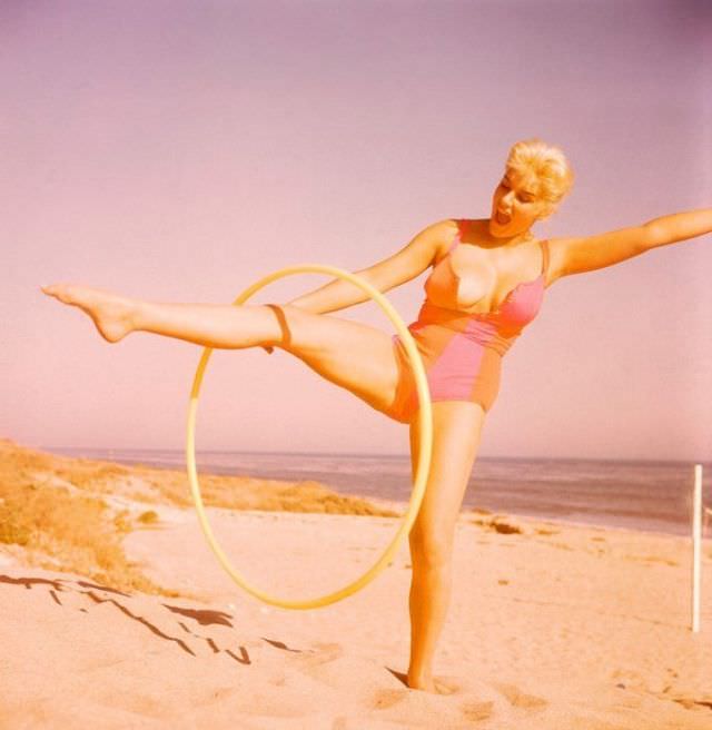 #28 June Wilkinson playing Hula Hoop on the beach, 1960s