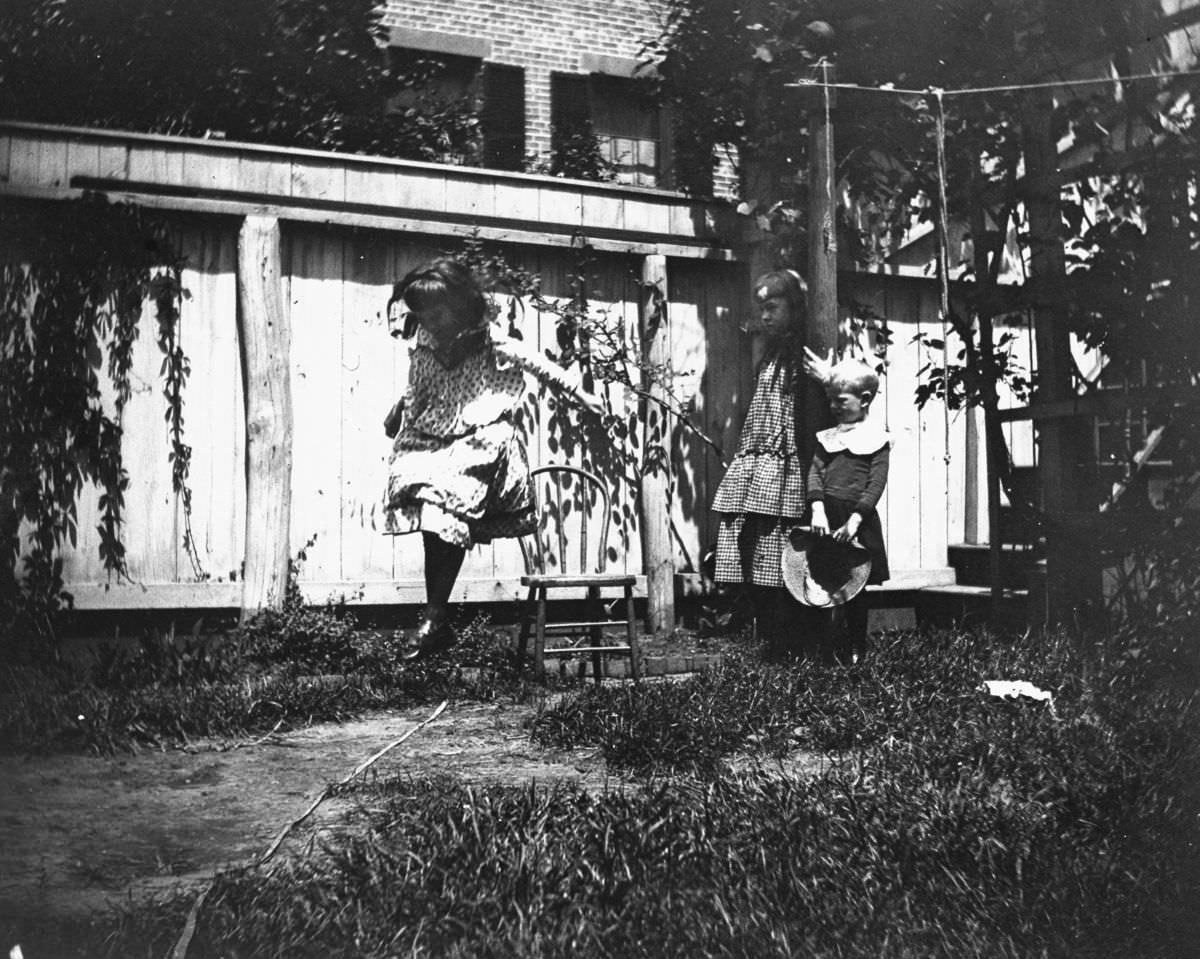 #36 Mildred Grimwood jumps in the backyard at 314 Livingston Street as brother Victor Grimwood and pal Zelma Levison look on.June 20, 1886