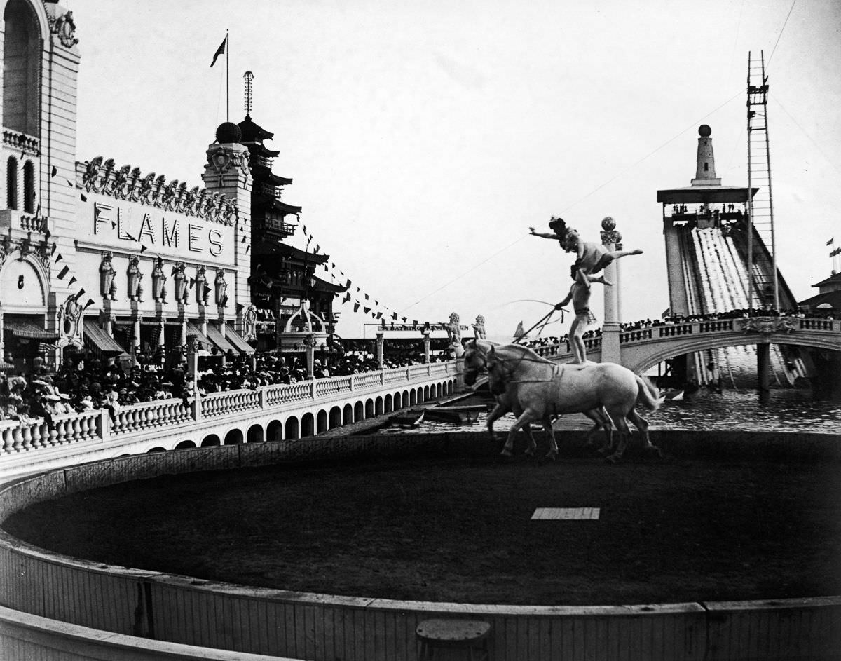 #28 Acrobats perform a balancing act on the backs of a pair of horses as crowds watch at Coney Island’s Dreamland