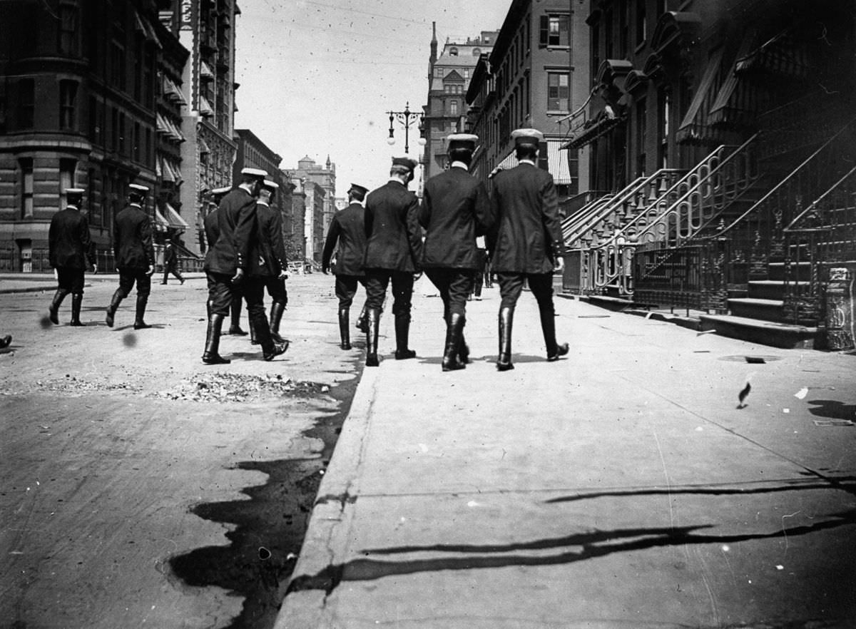#10 Uniformed officers in riding boots walk down a street, 1886
