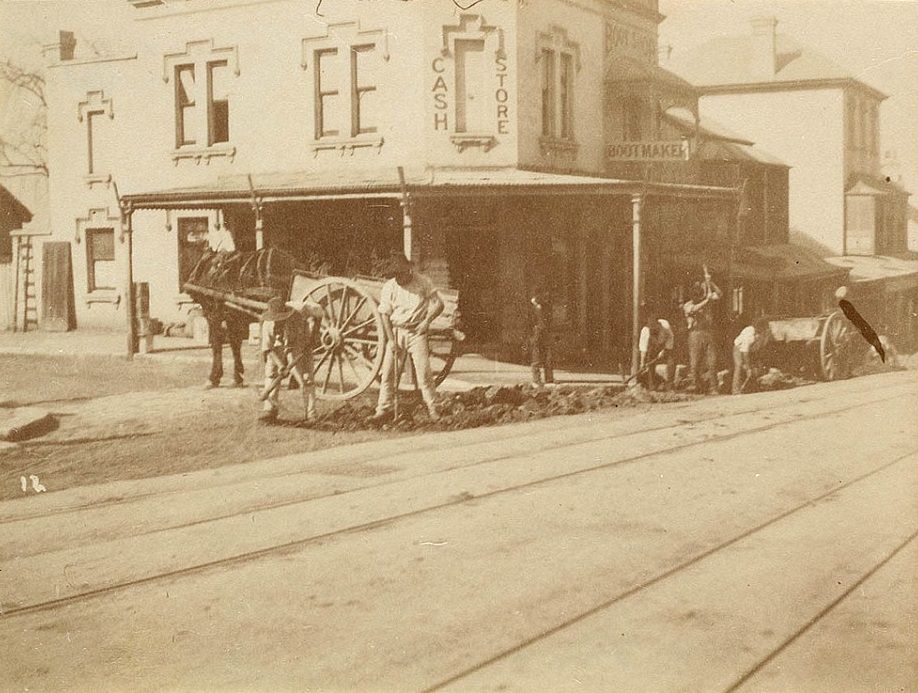 #35 Road workers are pictured digging trenches on the side of a street in Sydney, with horses and carts parked nearby, and tramlines visible in the foreground. Photo taken circa 1885-1890