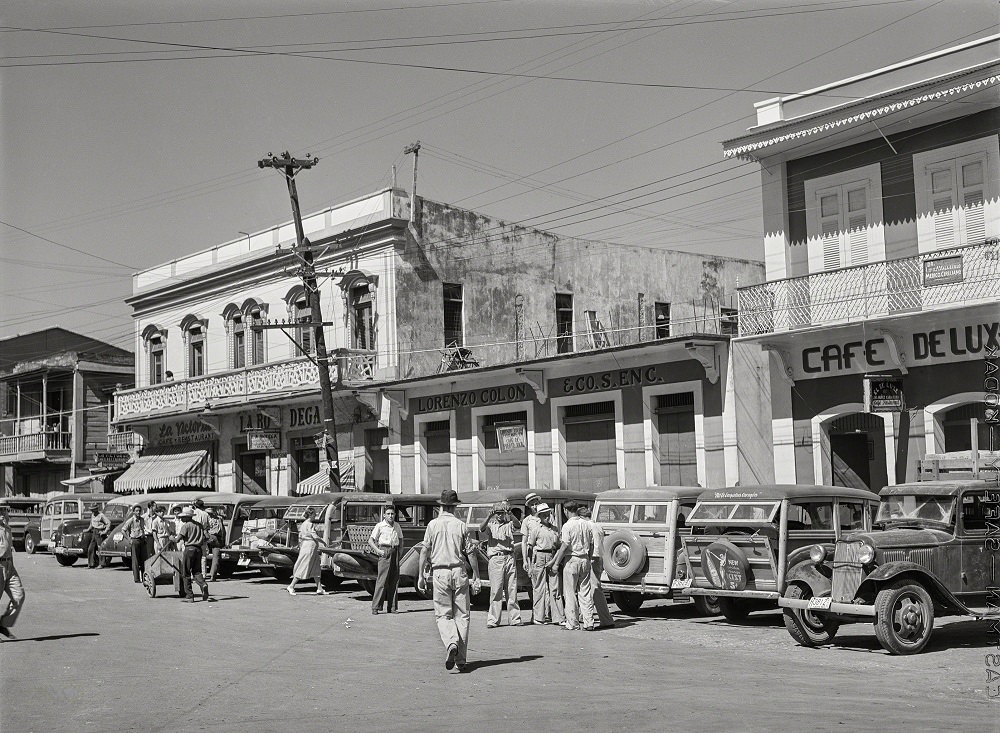 #16 A row of station wagons or ‘publicos’ waiting for loads and passengers, Arecibo, Puerto Rico, January 1942