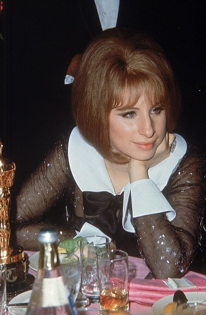#49 Barbra Streisand sitting at a table with her Best Actress Oscar award, 1969