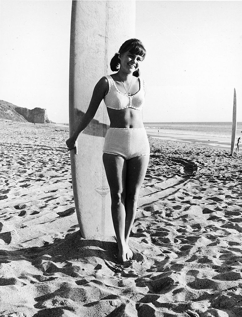 #29 Sally Field in a swimsuit with a surfboard on the beach, circa 1965