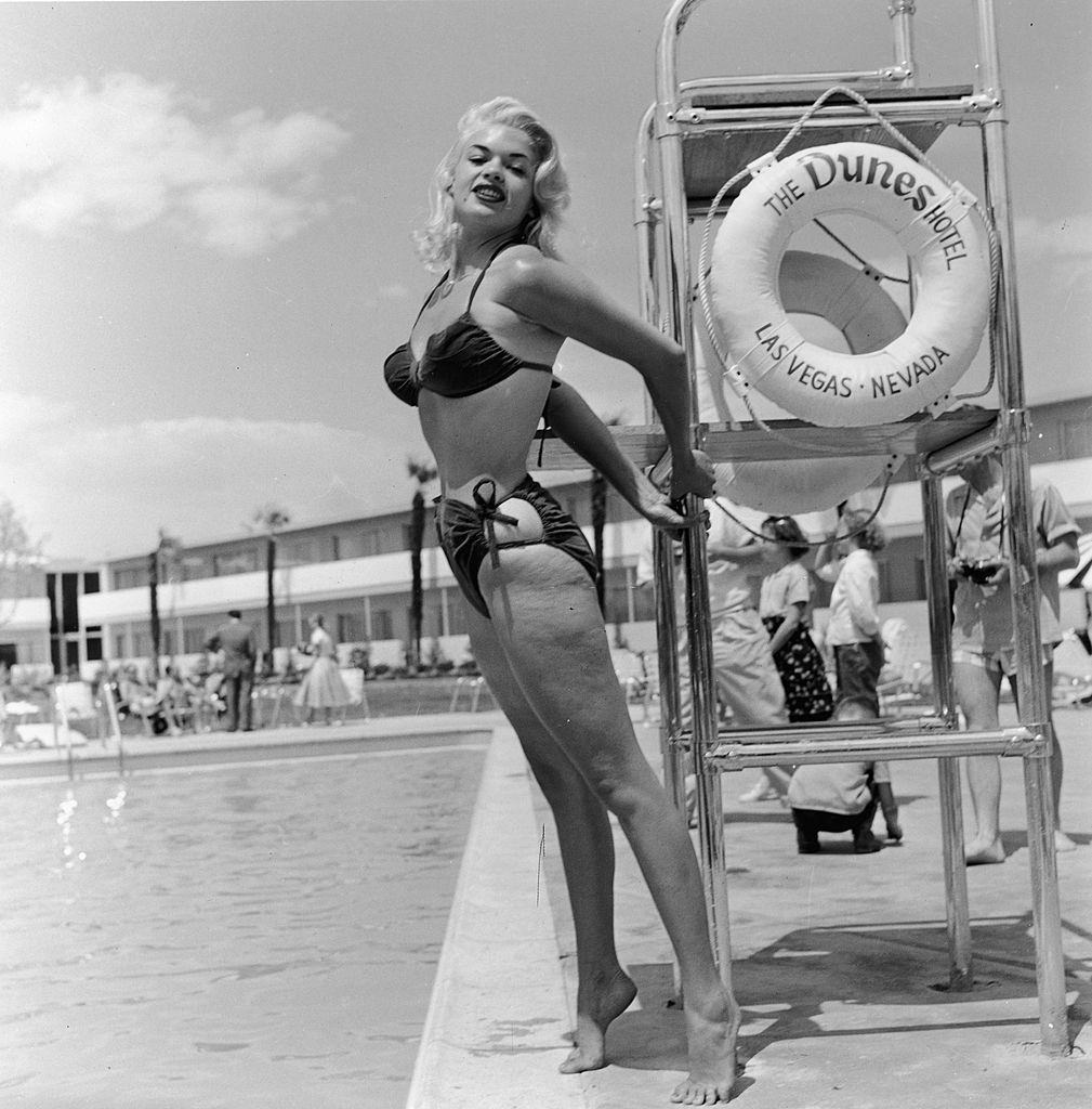#18 Jayne Mansfield poses in a bikini by a lifeguard chair at the Dunes Hotel, Las Vegas, 1950s