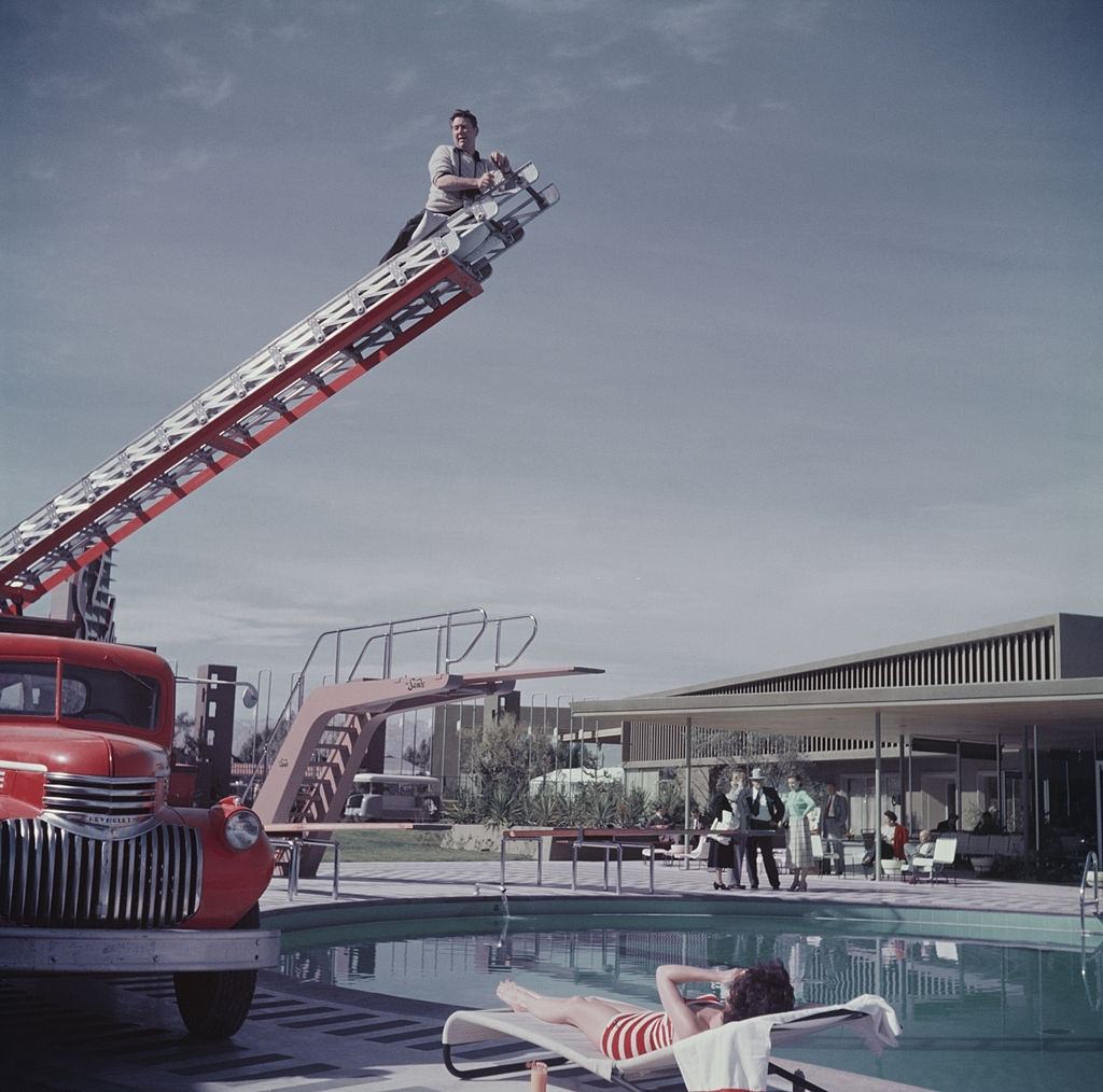 #47 Photographer Slim Aarons photographing film starlet Mara Lane from the top of an extending ladder by the swimming pool at Sands Hotel, Las Vegas, 1954.