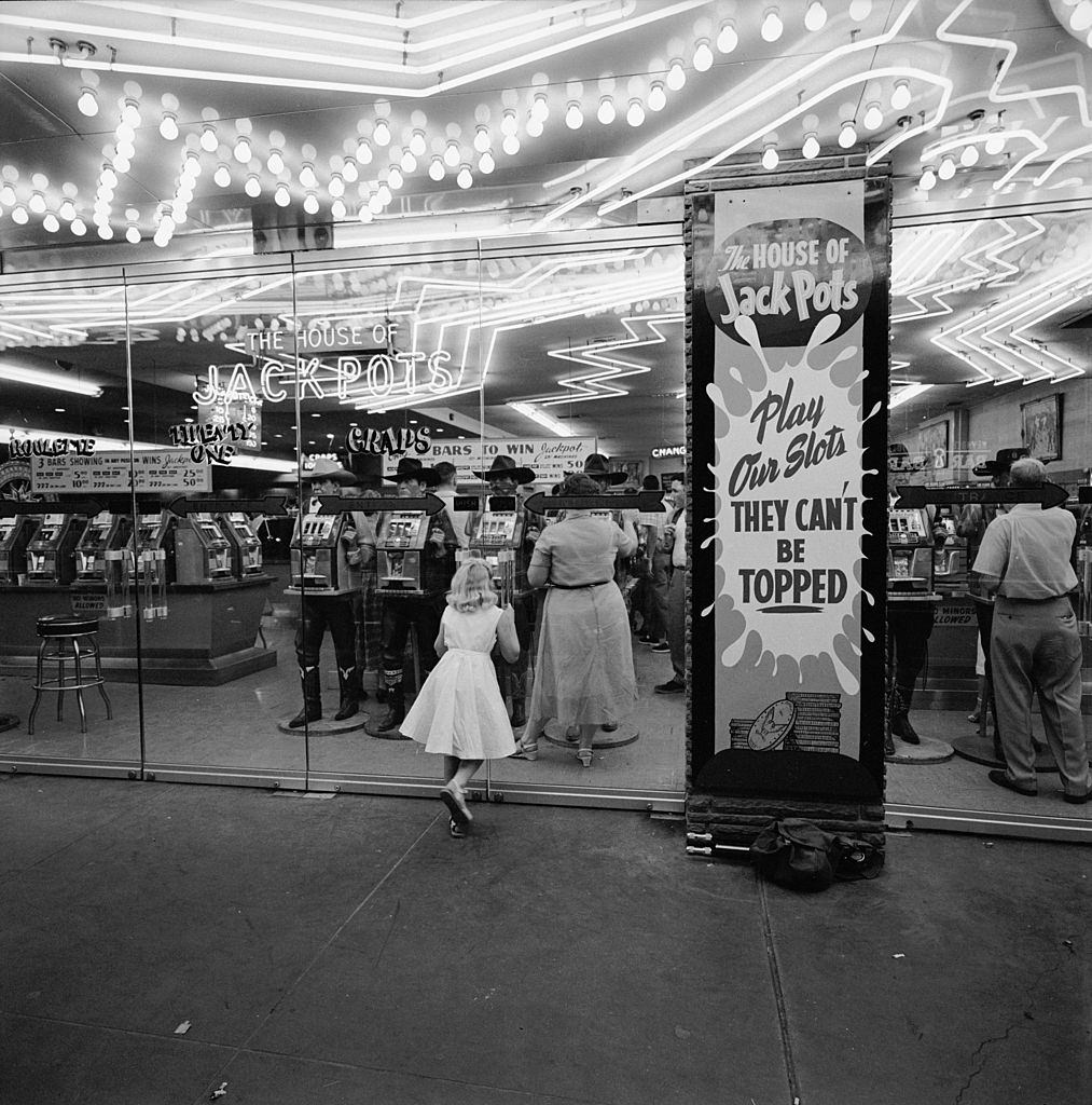 #59 A young girl looks at patrons and slot machines through the plate-glass windows at the ‘House of Jack Pots,’ Las Vegas, 1955.