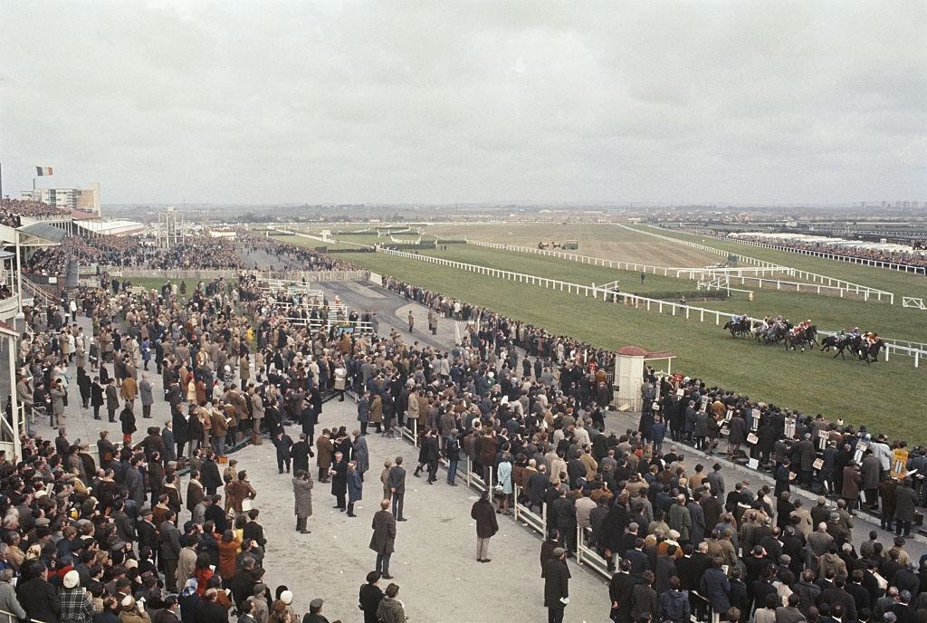 #24 View of race goers and spectators watching a National Hunt horse race from the grandstand on the day of the Grand National steeplechase race at Aintree racecourse, Liverpool, April 1970.
