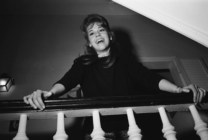 #22 Jane Fonda laughing while leaning at the banister of the stairs in her apartment.