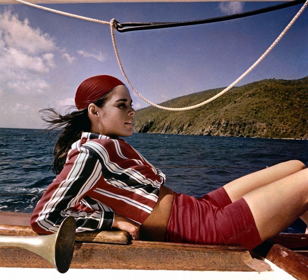 #16 Ali MacGraw reclining on a sailboat modelling a striped shirt and long shorts, 1967.