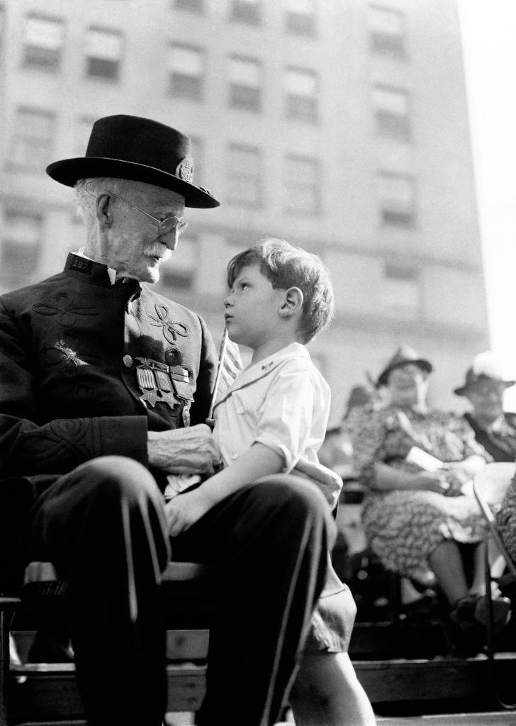 A Civil War Veteran sits with a child during a parade circa 1940’s in New York