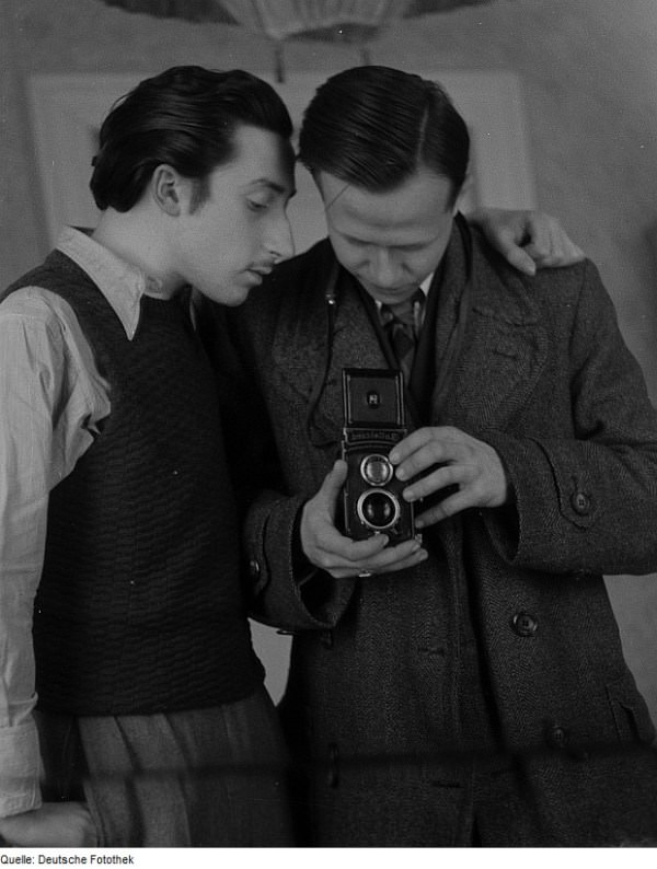 #25 German photographer Roger Rössing takes a mirror selfie as an unknown man looks on, 1947.