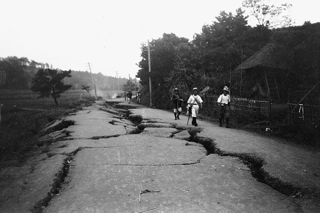#21 The earthquake survivors walk a damaged road in September 1923 in Totsuka, Kanagawa, Japan.