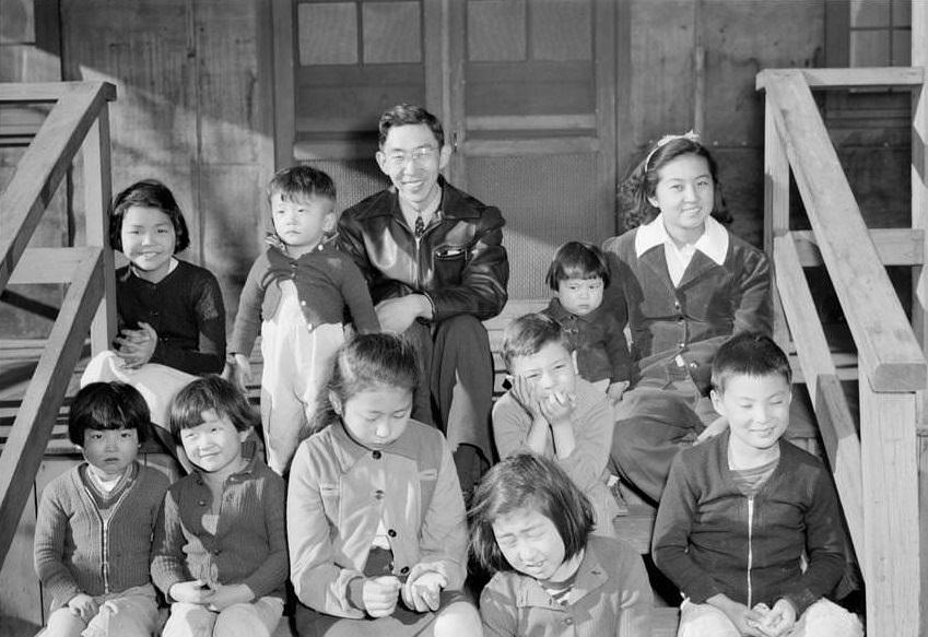 Man and woman seated on wooden steps with nine children.