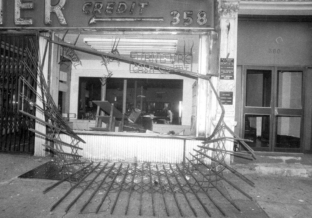 #17 Protective gate in front of store on Broadway between 145th and 165th Sts. lies twisted on the street after looting during 1977 blackout.