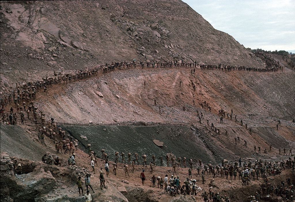#18 Mine workers, or garimpeiros, carry out 40-pound bags of ore from their owners mining claims July 15, 1985 in Serra Pelada, Brazil.