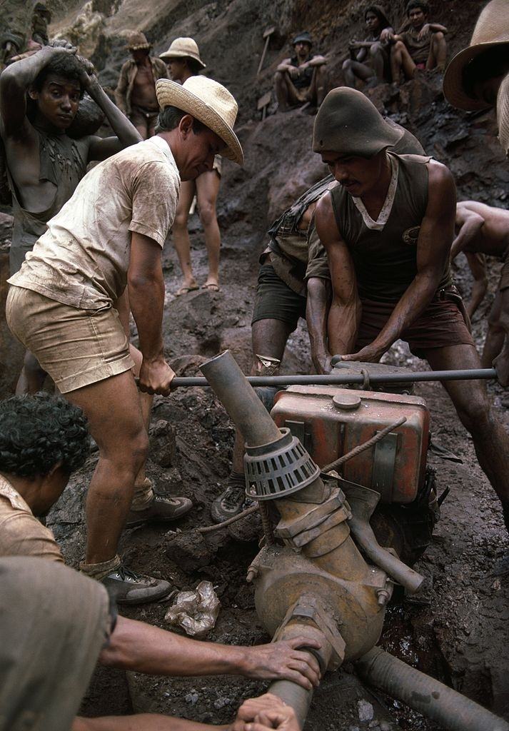 #23 Mine workers carry a water pump to drain water, in Serra Pelada, Brazil.