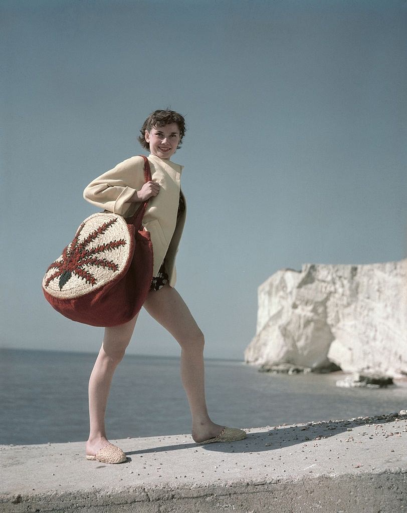 #58 Audrey Hepburn at the seaside whilst carrying a shoulder bag, 1952.