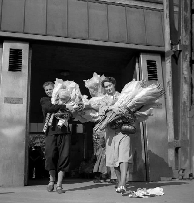 #15 A young man and a woman with large flower bundles outside Klarahallen.