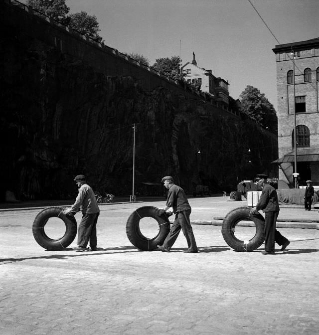 #26 Harbor workers rolling truck tires over the dock, Stadsgården.