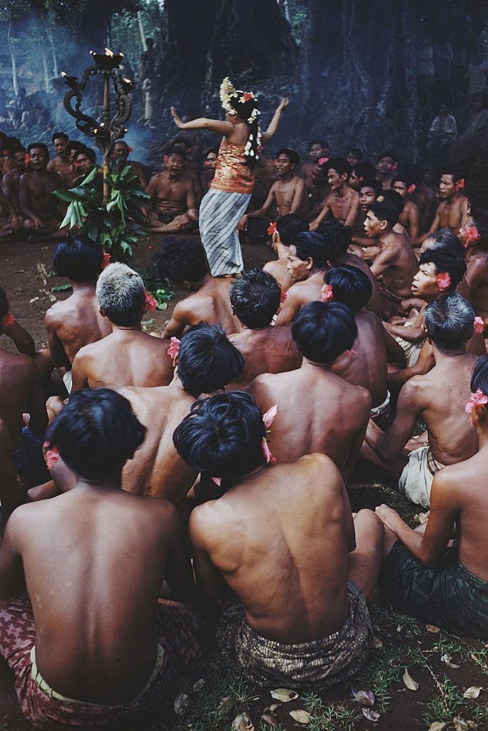 #21 Stripped to the waist Balinese men watch a woman dance round a ‘totem’, 1956.