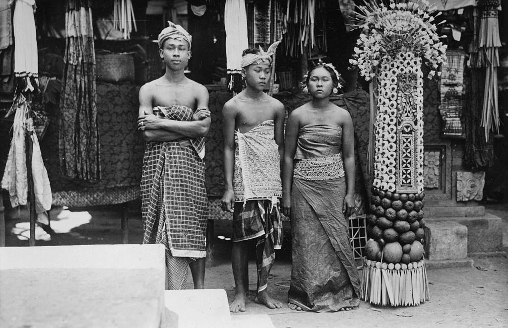 #33 Three young Indonesians standing by a votive made from fruit and flowers in Bali, 1951.