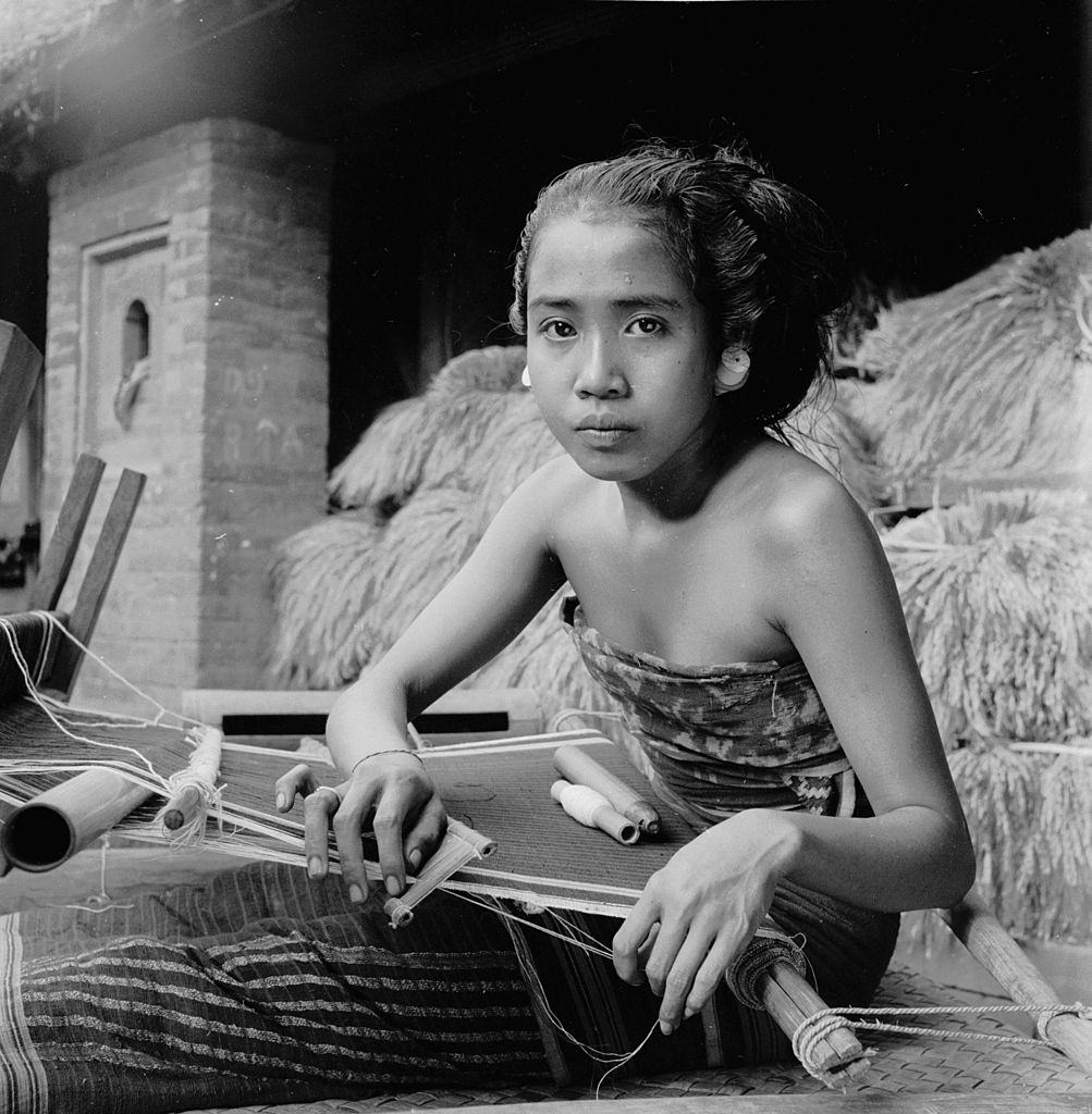 #38 An Indonesian woman weaving on the island of Bali, 1955.