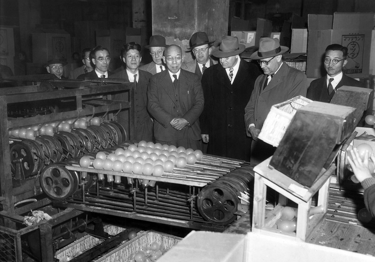 #7 Industrial training experts watch a light bulb machine drop bulbs down to other workers who sort them according to defects at Tokyo Shibaura Electric Co. in Tokyo on January 25, 1951.